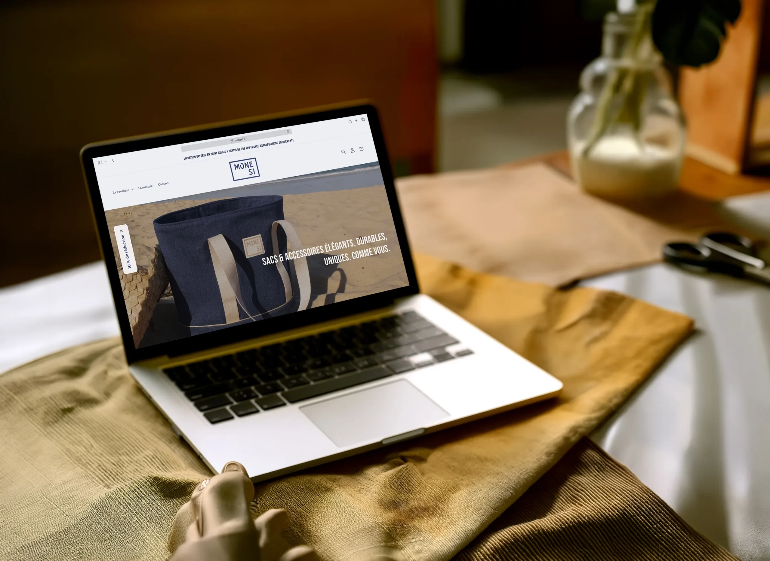 Site Internet MoneSi version desktop avec macbook, arrière-plan de tissus